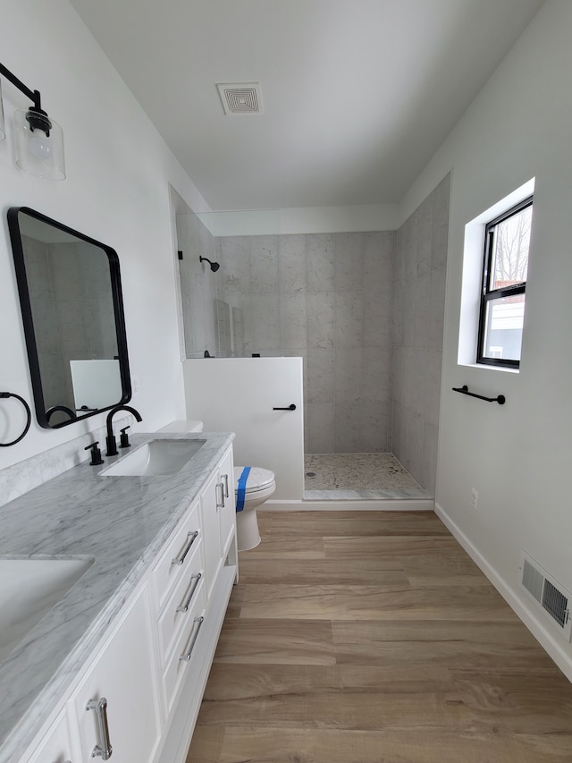 full bath featuring double vanity, visible vents, toilet, walk in shower, and a sink