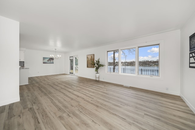 unfurnished living room with an inviting chandelier, light hardwood / wood-style flooring, crown molding, and a water view