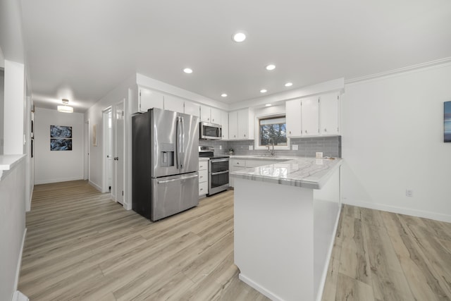 kitchen with light hardwood / wood-style floors, kitchen peninsula, stainless steel appliances, and white cabinetry