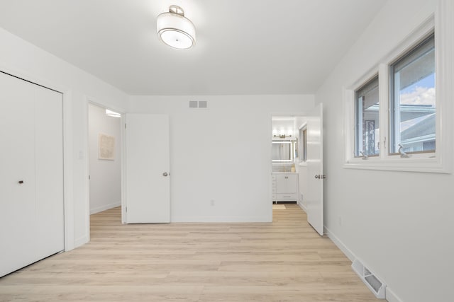 unfurnished bedroom with light hardwood / wood-style floors, connected bathroom, and a closet