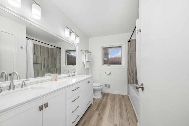 full bathroom with hardwood / wood-style floors, vanity, toilet, and shower / bathtub combination with curtain