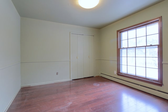 empty room with baseboard heating and wood-type flooring