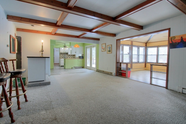 unfurnished living room with ceiling fan, beamed ceiling, light colored carpet, and a baseboard radiator