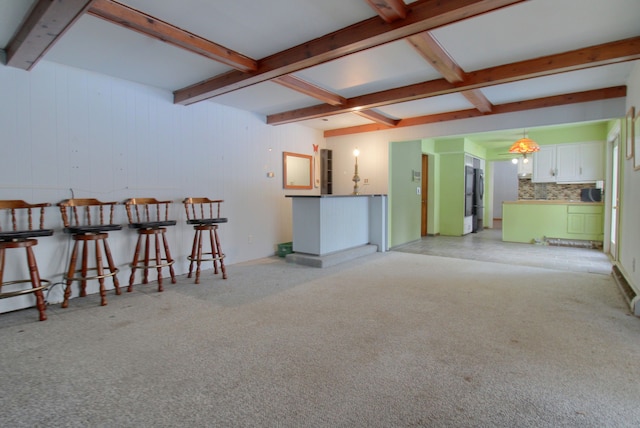 living room with wood walls, beam ceiling, and light colored carpet