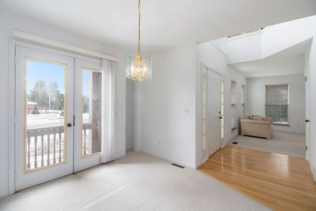 unfurnished dining area featuring french doors, wood-type flooring, and a notable chandelier