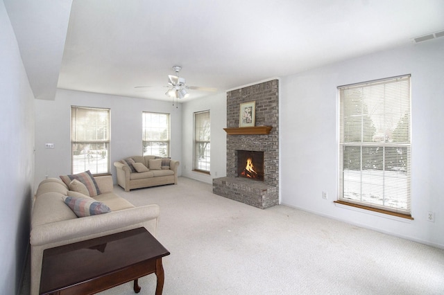 living room featuring a fireplace, light colored carpet, and ceiling fan