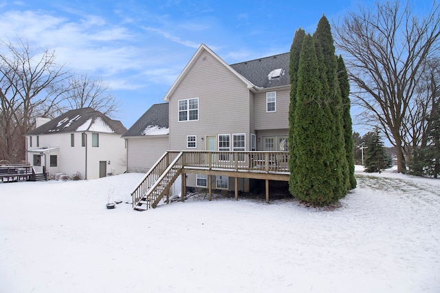 snow covered back of property featuring a wooden deck