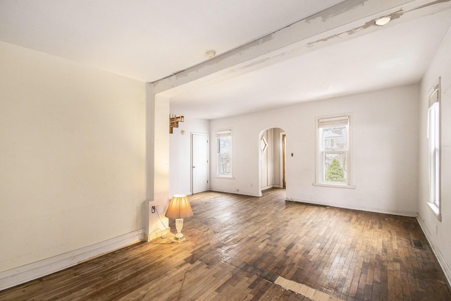 unfurnished room with beam ceiling and dark wood-type flooring