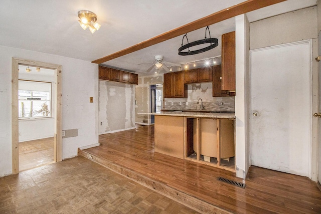 kitchen with dark parquet flooring, ceiling fan, sink, backsplash, and kitchen peninsula