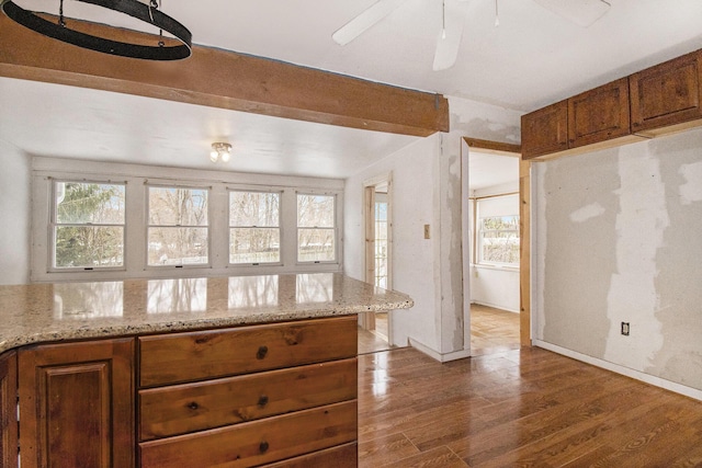 kitchen with hardwood / wood-style floors, ceiling fan, a healthy amount of sunlight, and light stone countertops