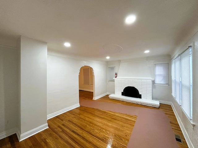 unfurnished living room with hardwood / wood-style flooring and a brick fireplace