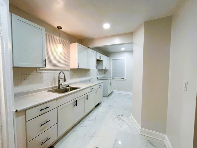 kitchen with backsplash, white cabinetry, hanging light fixtures, and sink