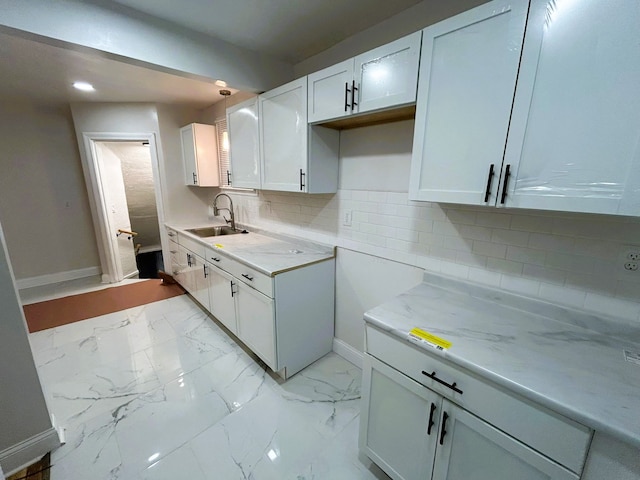 kitchen with decorative backsplash, sink, white cabinets, and light stone countertops