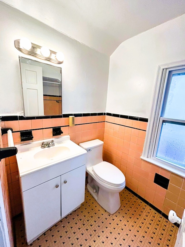 bathroom with tile patterned floors, vanity, toilet, and tile walls