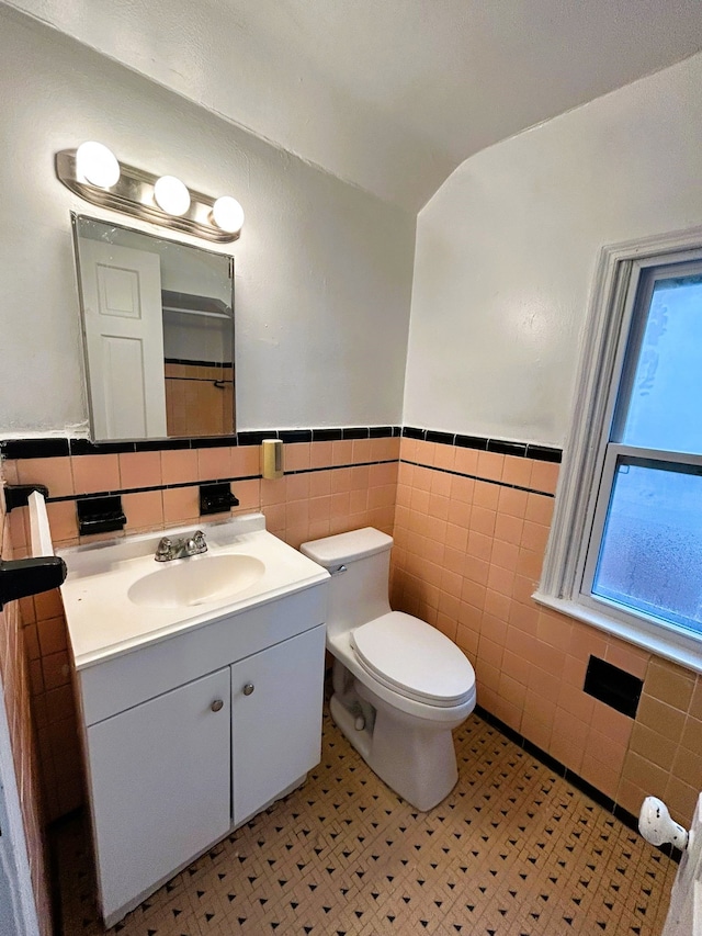 bathroom with tile patterned floors, vanity, toilet, and tile walls