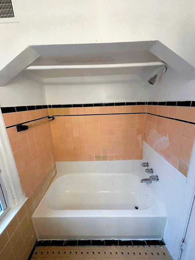 bathroom featuring tile patterned floors, a tub, and tile walls