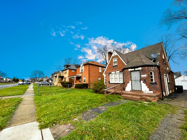 view of side of home featuring brick siding, a residential view, a lawn, a chimney, and a shingled roof