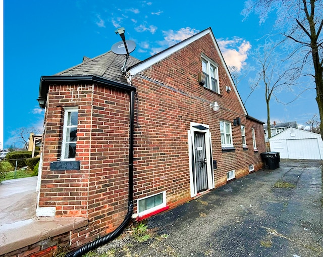 view of side of home with brick siding and an outdoor structure