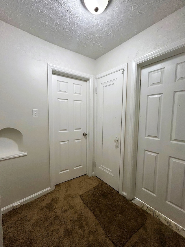 entryway with dark carpet and a textured ceiling