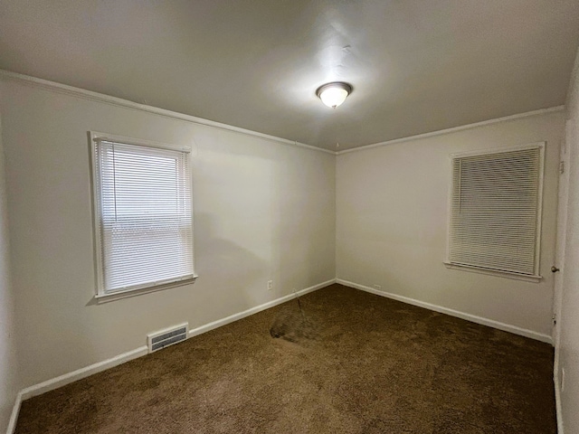 spare room featuring ornamental molding and dark carpet