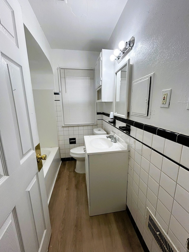 bathroom with radiator, vanity, hardwood / wood-style flooring, tile walls, and toilet