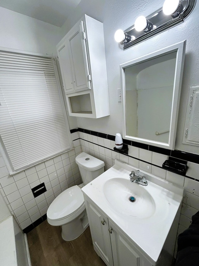 bathroom with wood-type flooring, vanity, toilet, and tile walls