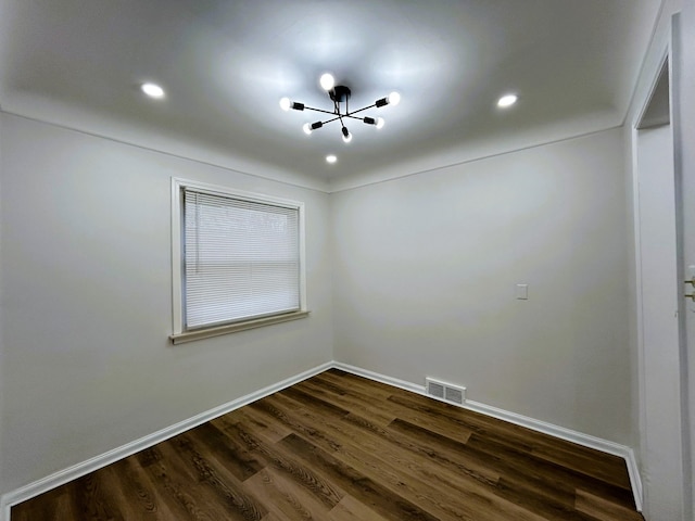 empty room featuring dark hardwood / wood-style flooring and a notable chandelier