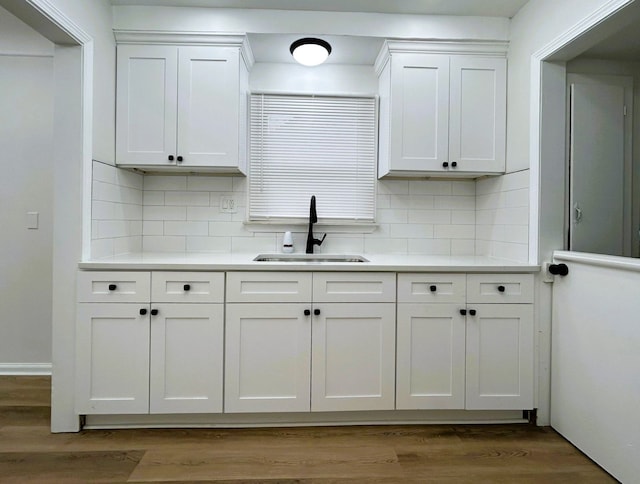 kitchen with decorative backsplash, sink, white cabinets, and hardwood / wood-style floors