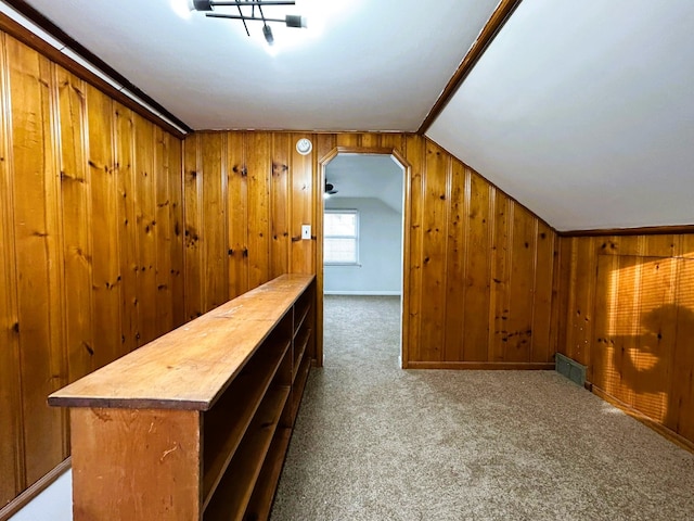 bar featuring wooden counters, light carpet, vaulted ceiling, and wood walls