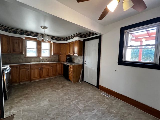 kitchen featuring sink, black dishwasher, hanging light fixtures, and backsplash