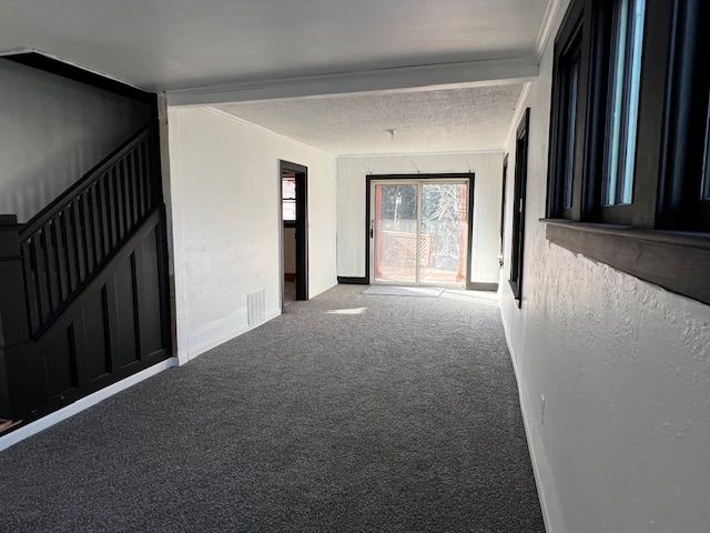 unfurnished room with carpet flooring and beam ceiling