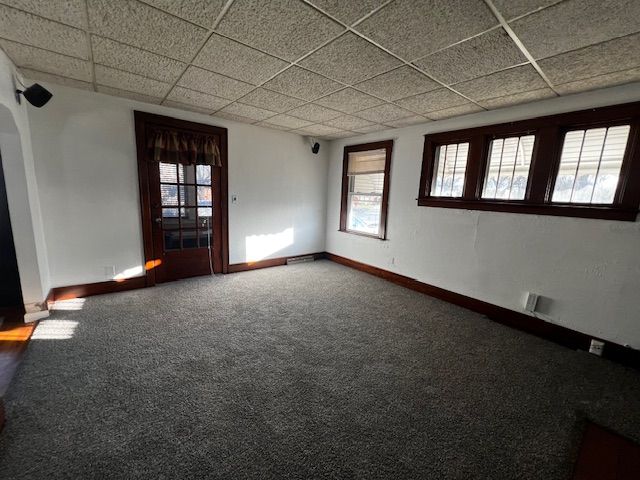 unfurnished room with carpet flooring, a drop ceiling, and plenty of natural light