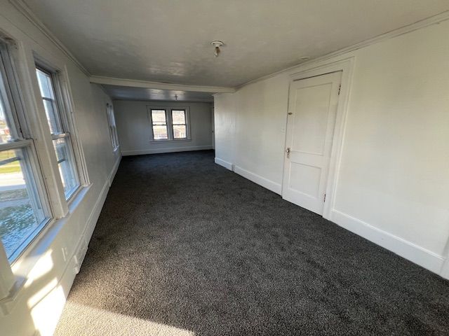 unfurnished room with dark carpet and ornamental molding