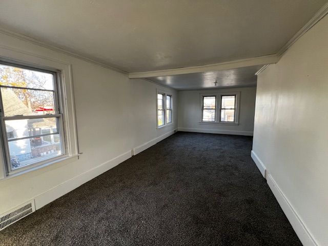 empty room with dark carpet and ornamental molding