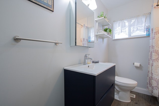 bathroom with hardwood / wood-style flooring, vanity, toilet, and walk in shower