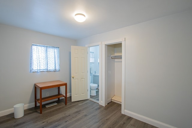 bedroom with dark hardwood / wood-style flooring, a closet, and connected bathroom