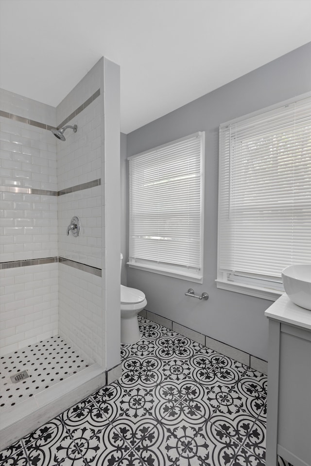 bathroom with a tile shower, tile patterned floors, vanity, and toilet