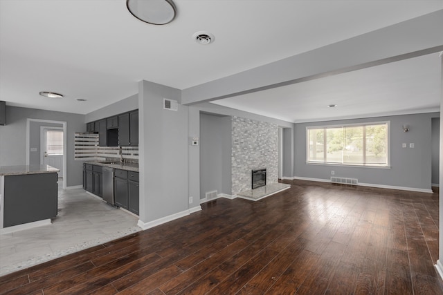 unfurnished living room featuring dark hardwood / wood-style floors, sink, and a fireplace