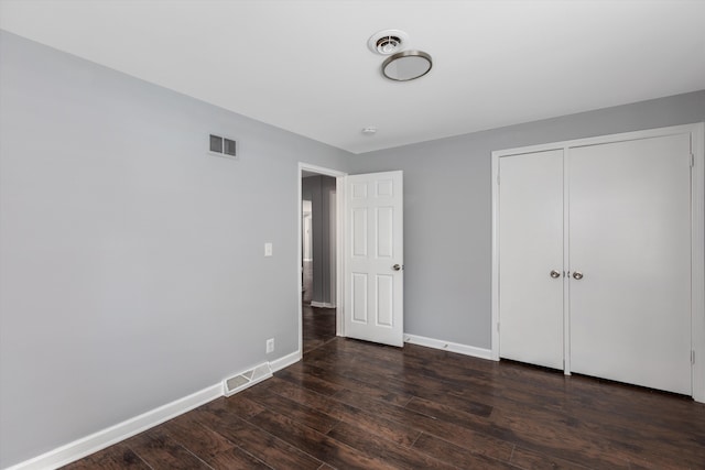 unfurnished bedroom with dark hardwood / wood-style floors and a closet