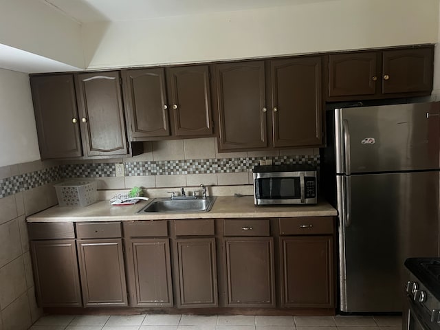 kitchen with sink, light tile patterned flooring, stainless steel appliances, and dark brown cabinets