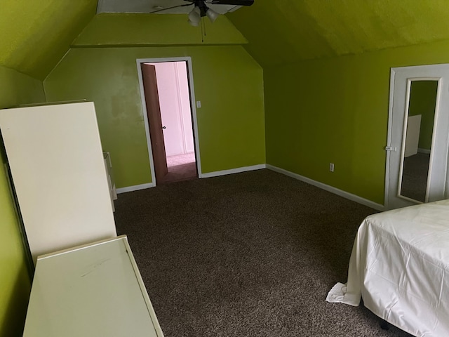 unfurnished bedroom with dark colored carpet, ceiling fan, and lofted ceiling