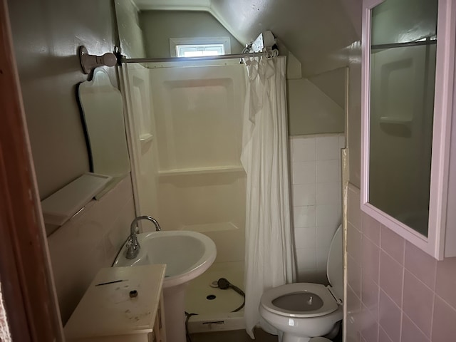 bathroom with sink, curtained shower, toilet, and tile walls