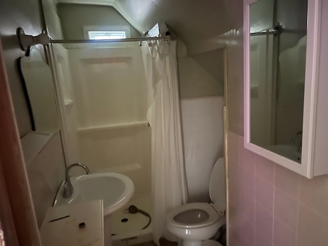 bathroom featuring lofted ceiling, a shower with curtain, sink, toilet, and tile walls