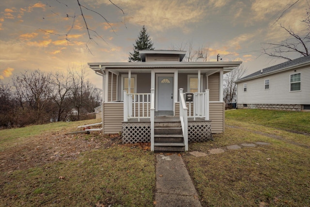 bungalow-style home with a yard and covered porch