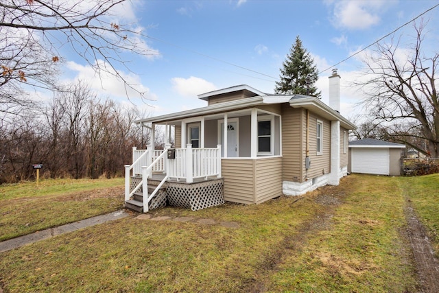 bungalow-style home featuring a porch, a garage, an outdoor structure, and a front yard