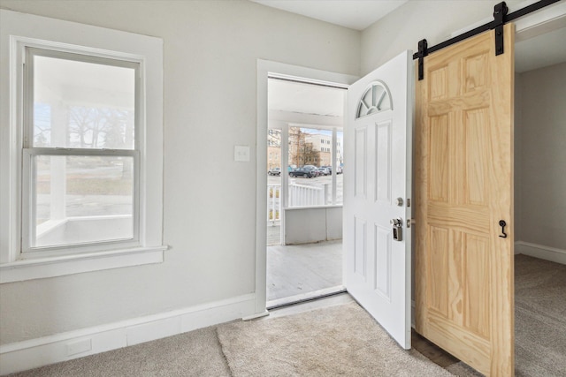 entrance foyer with a barn door and carpet floors