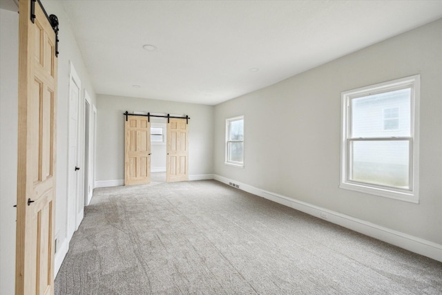 unfurnished bedroom featuring a barn door and carpet