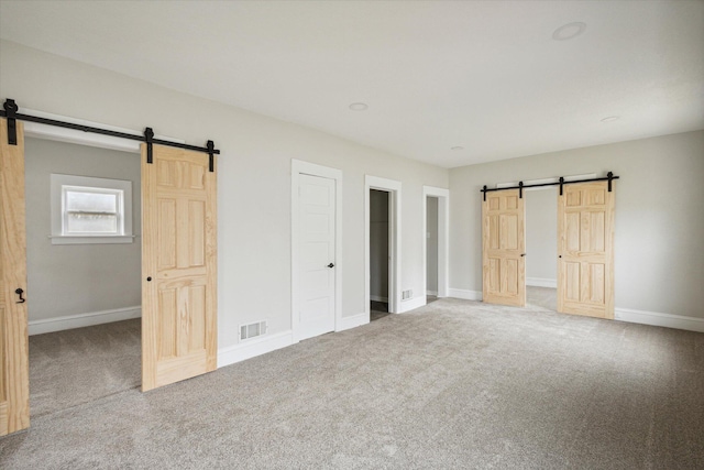 unfurnished bedroom with carpet, a barn door, and a closet