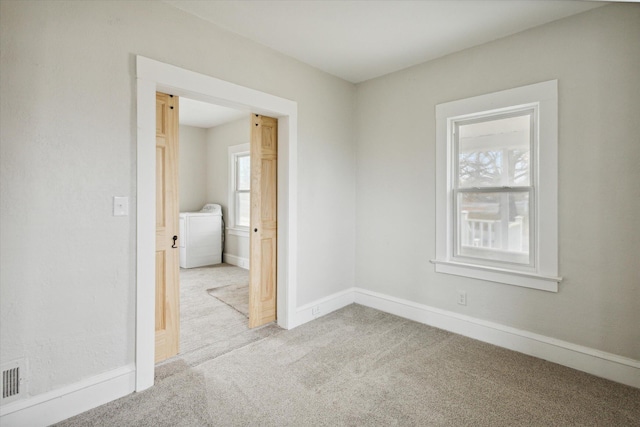 carpeted spare room with a healthy amount of sunlight and washer / clothes dryer