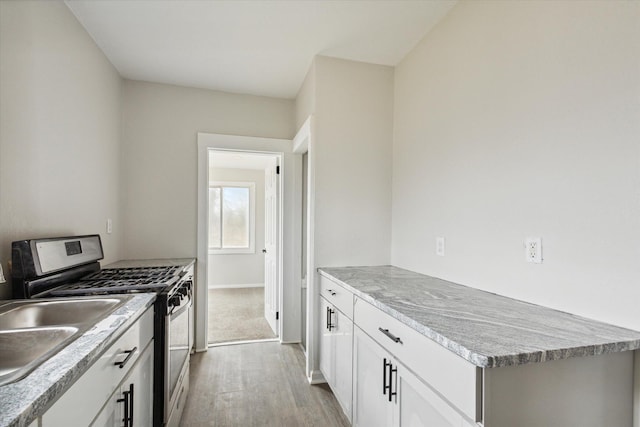 kitchen with light wood-type flooring, white cabinetry, and stainless steel range with gas stovetop